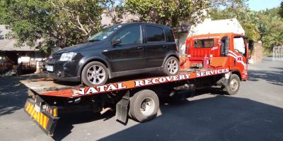Small black car on a tow-in truck